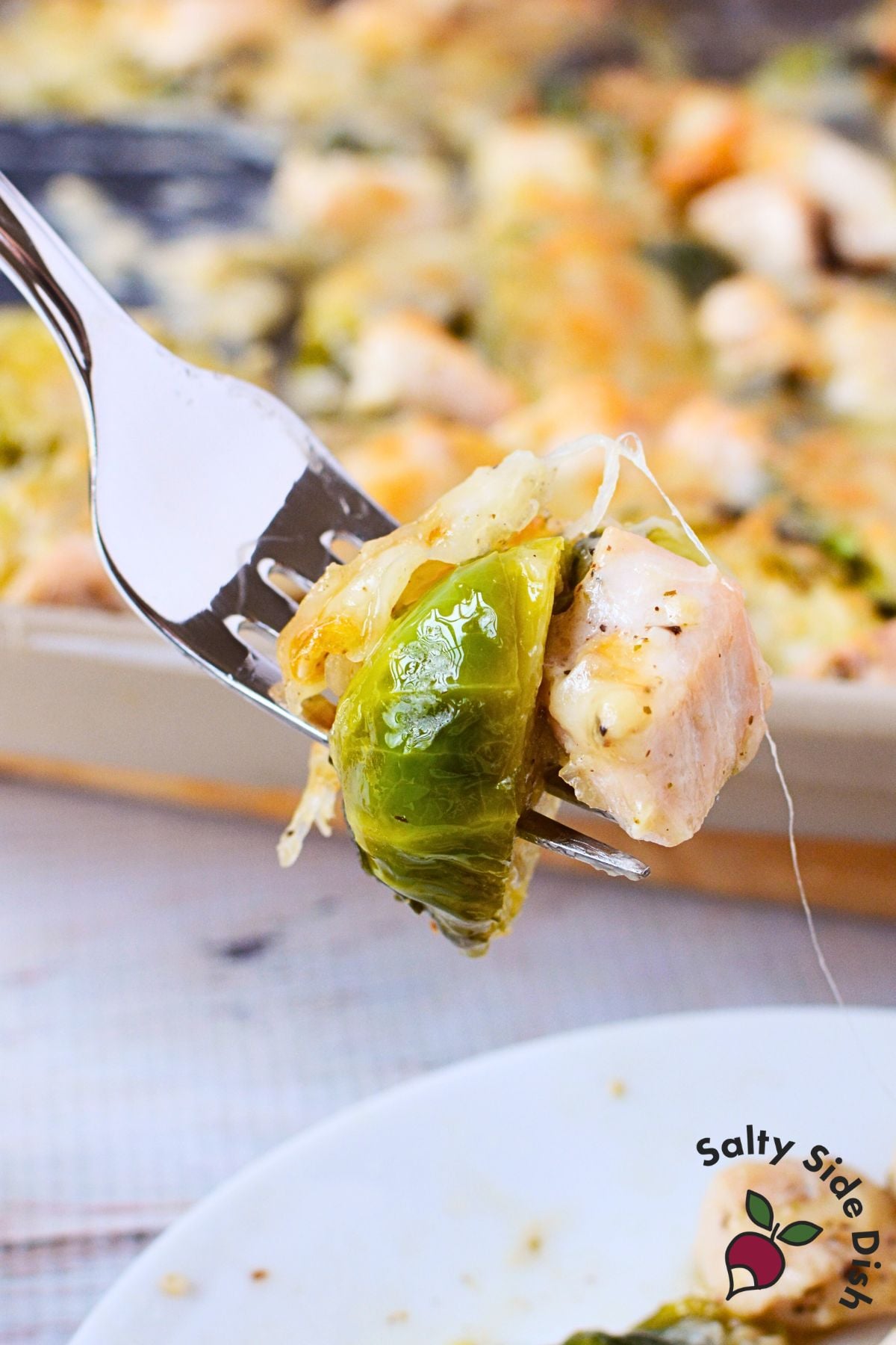sheet pan garlic chicken and brussels sprouts with melted gruyere served on a white plate with a fork