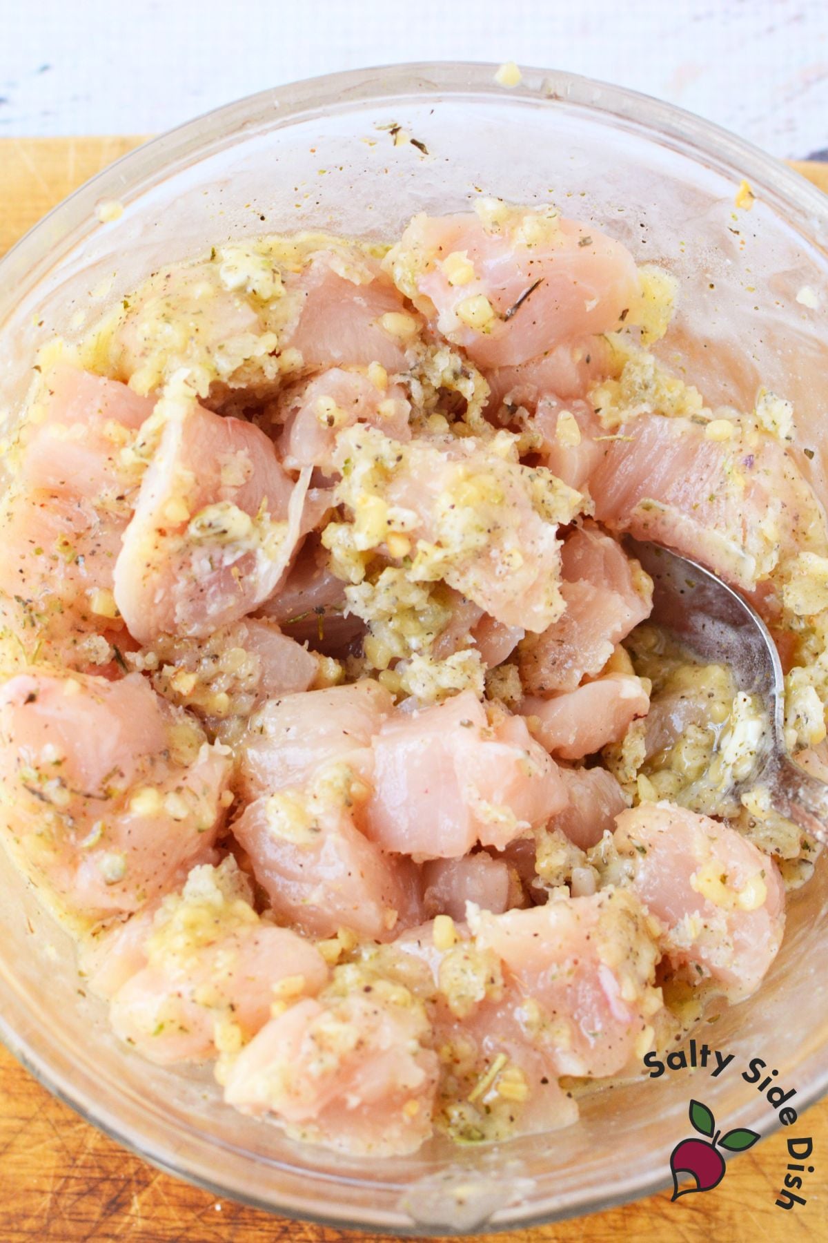 raw chicken breast chunks tossed in garlic butter and Italian seasoning in a glass mixing bowl