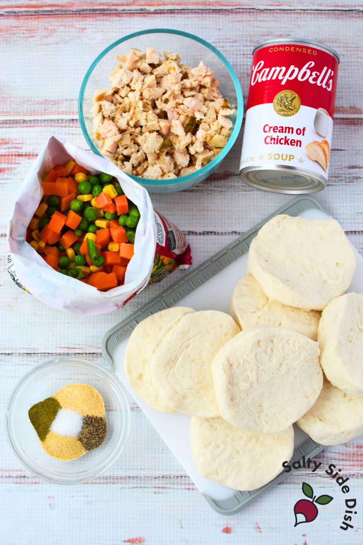 Ingredients for chicken pot pie cups including canned biscuits, cream of chicken soup, diced cooked chicken, frozen mixed vegetables, and spices