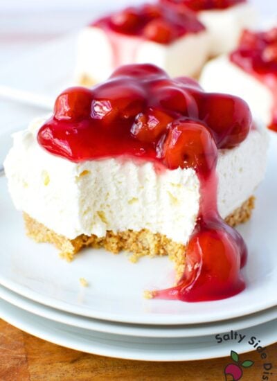 easy no bake cherry cheesecake bar with a bite taken out showing fluffy cream cheese filling and graham cracker crust