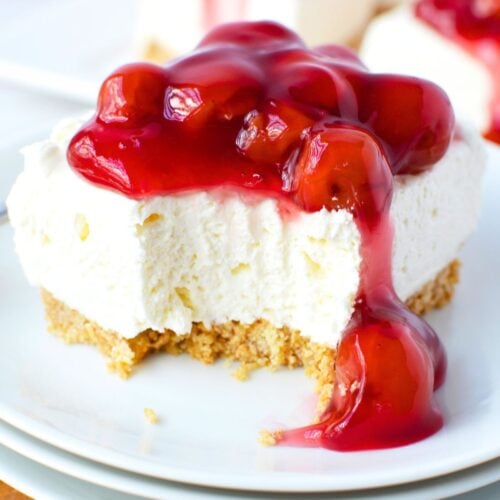 easy no bake cherry cheesecake bar with a bite taken out showing fluffy cream cheese filling and graham cracker crust