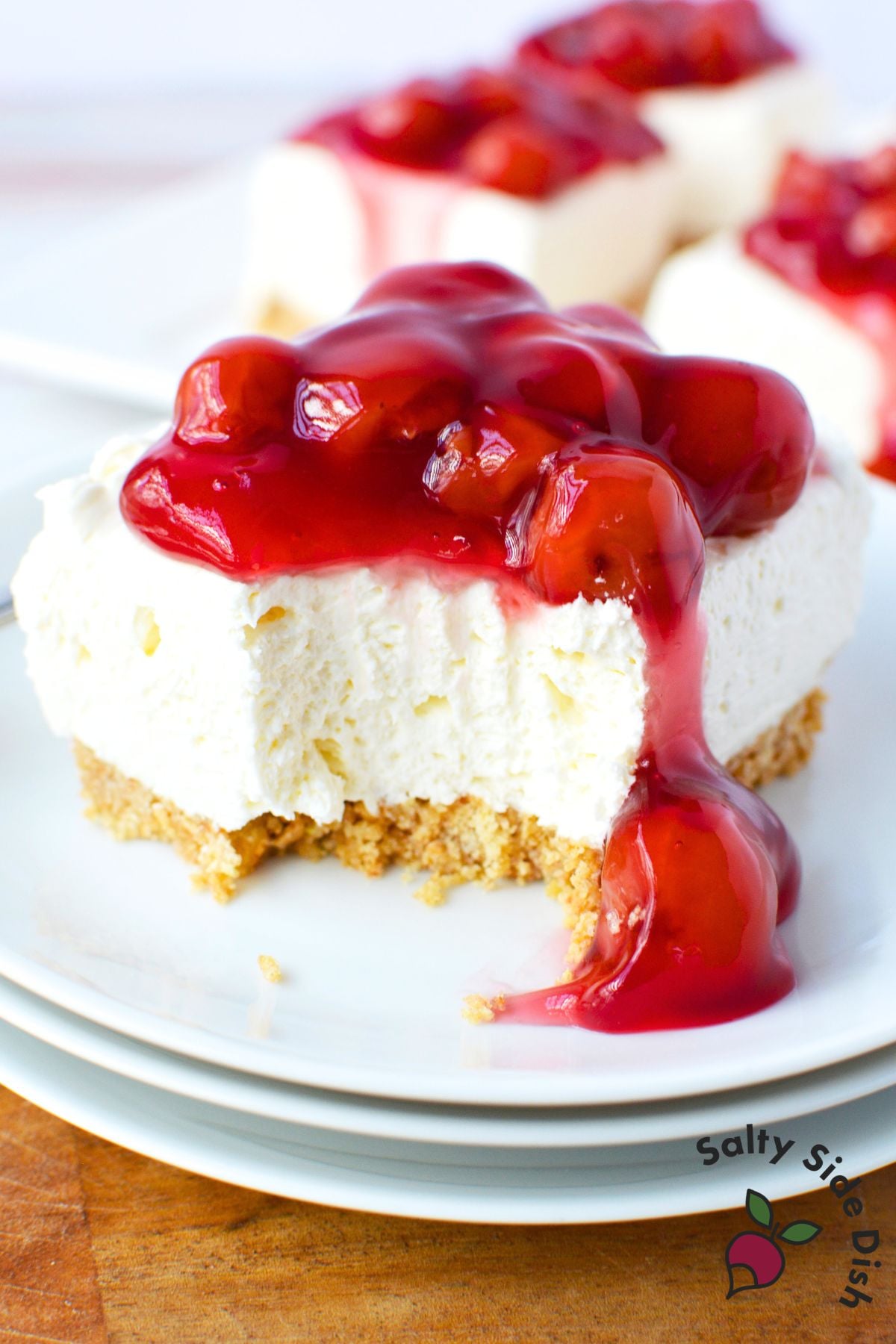 easy no bake cherry cheesecake bar with a bite taken out showing fluffy cream cheese filling and graham cracker crust