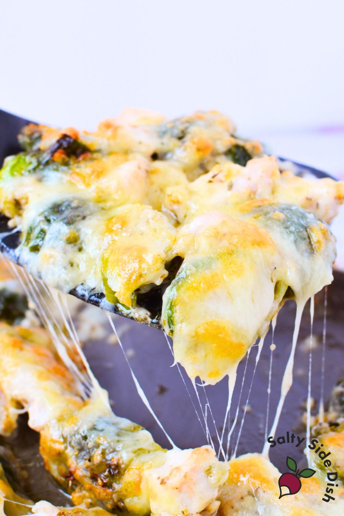 sheet pan chicken and brussels sprouts covered in melted bubbly gruyere cheese fresh out of the oven