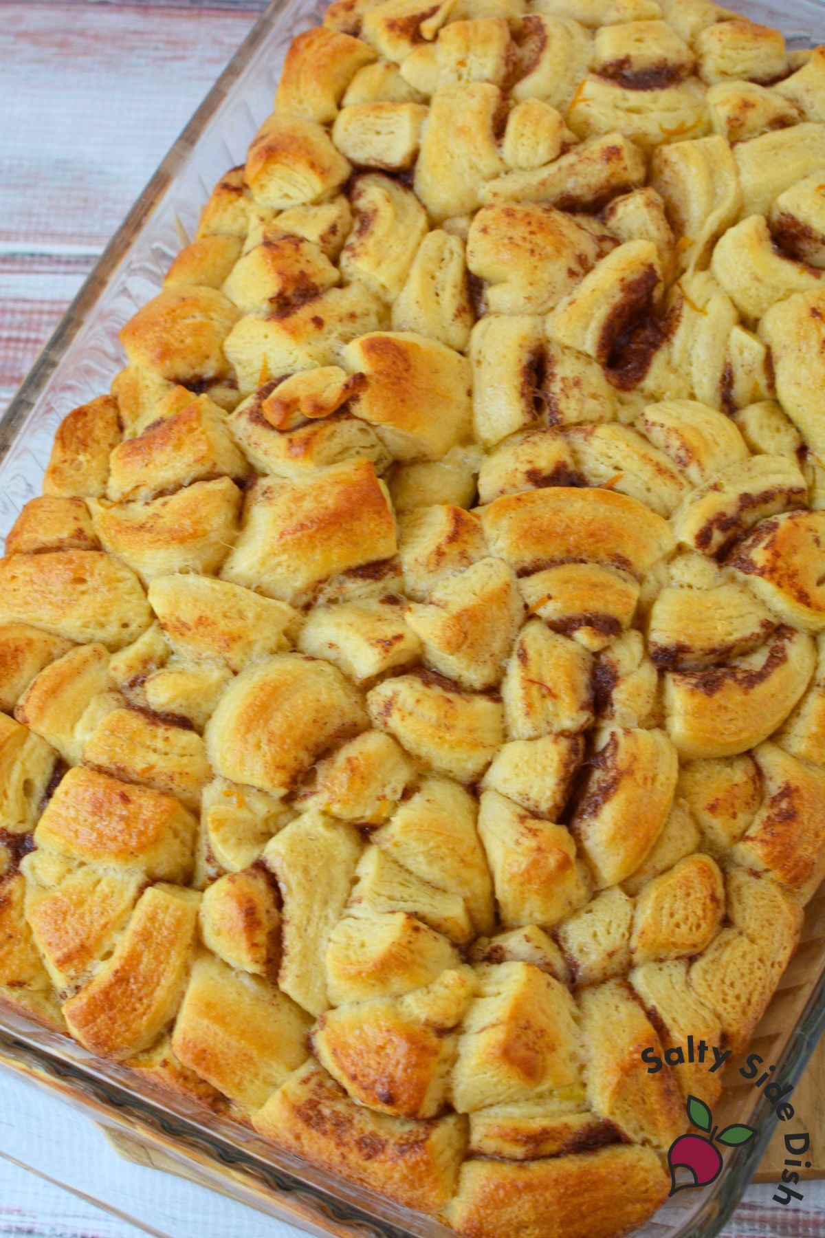 Baked orange roll casserole in a glass 9x13 dish, golden brown with visible cinnamon swirls on top