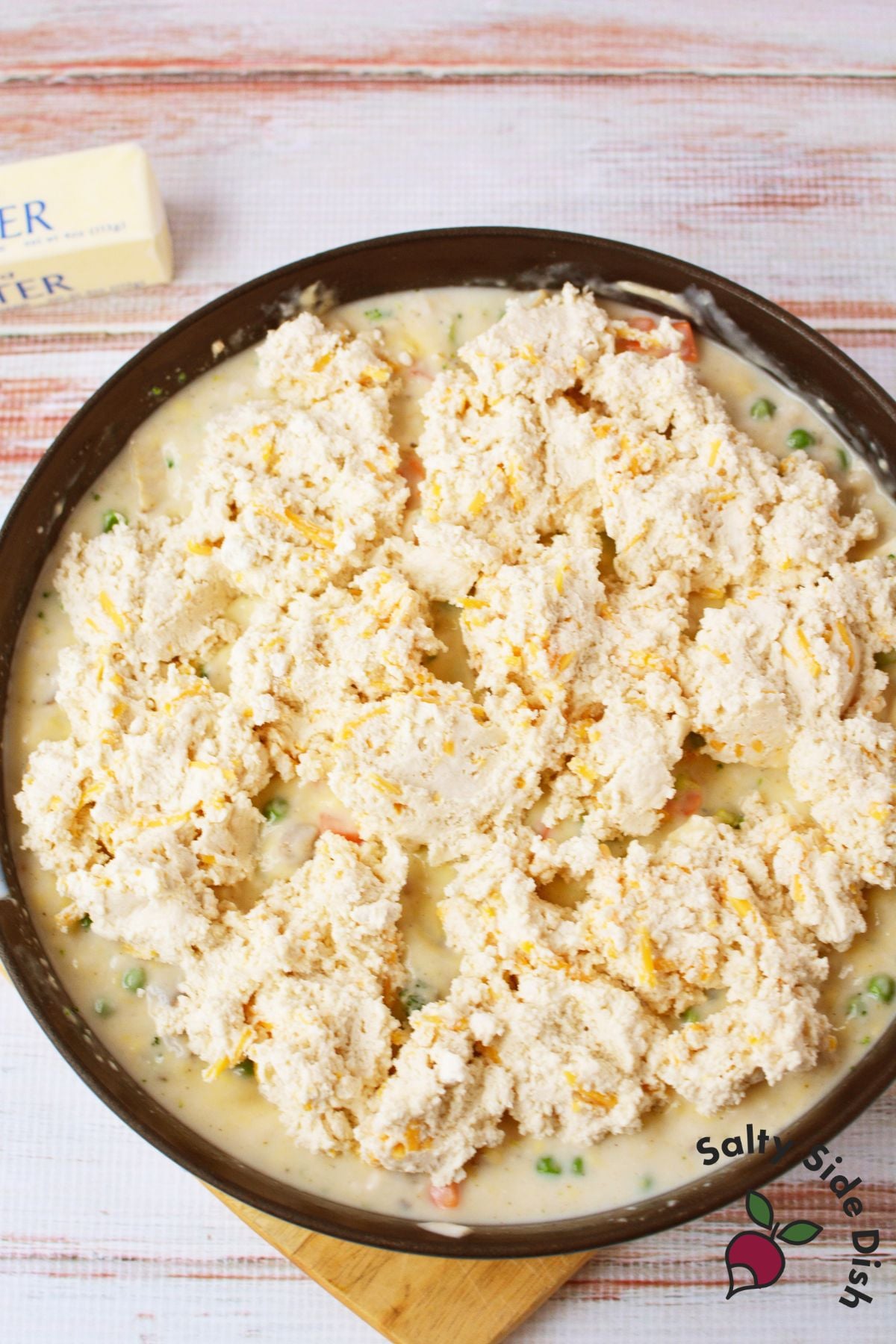 Unbaked Cheddar Bay Biscuit dough dropped in spoonfuls over creamy chicken pot pie filling in a round baking dish