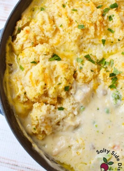 Golden baked Cheddar Bay Biscuit topping on chicken pot pie in a cast iron skillet garnished with fresh parsley