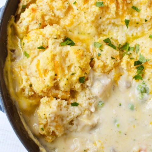 Golden baked Cheddar Bay Biscuit topping on chicken pot pie in a cast iron skillet garnished with fresh parsley