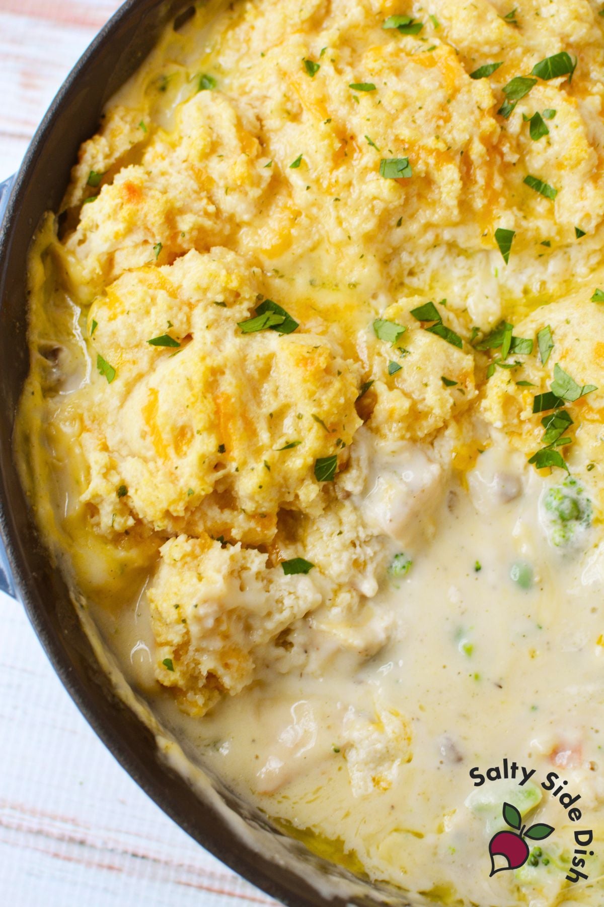 Golden baked Cheddar Bay Biscuit topping on chicken pot pie in a cast iron skillet garnished with fresh parsley