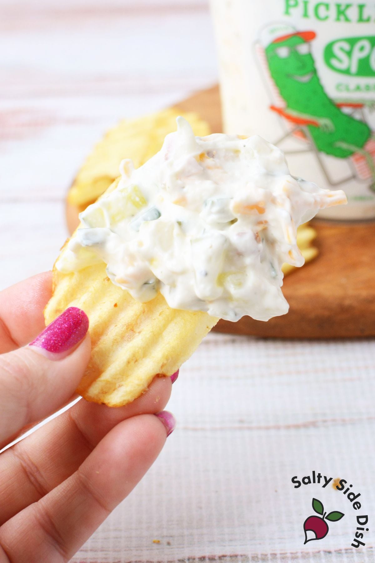 Hand dipping a potato chip into creamy Grillo’s pickle dip