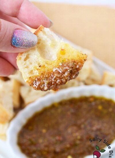 Crusty bread dipped into seasoned olive oil parmesan balsamic bread dip close up