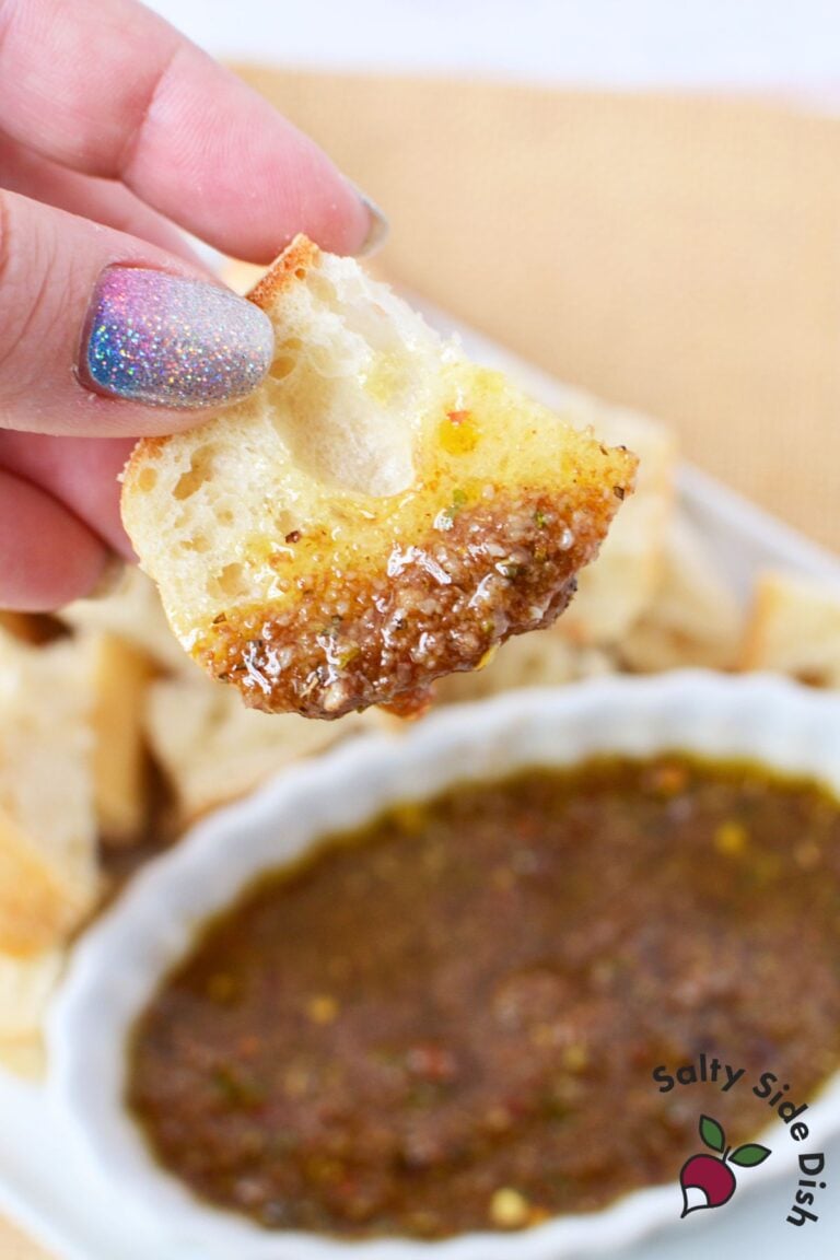 Crusty bread dipped into seasoned olive oil parmesan balsamic bread dip close up