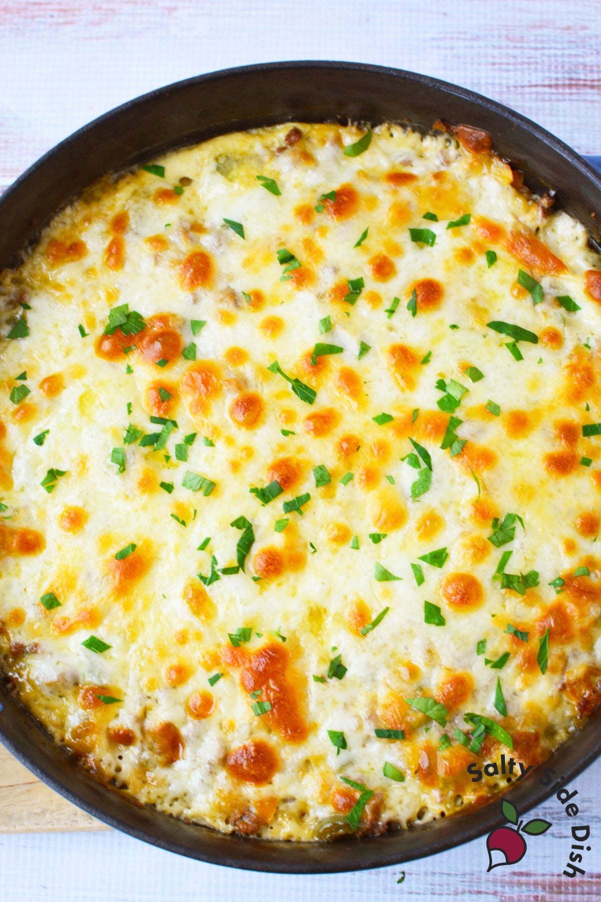 Overhead view of baked philly cheesesteak casserole with golden melted cheese and fresh parsley