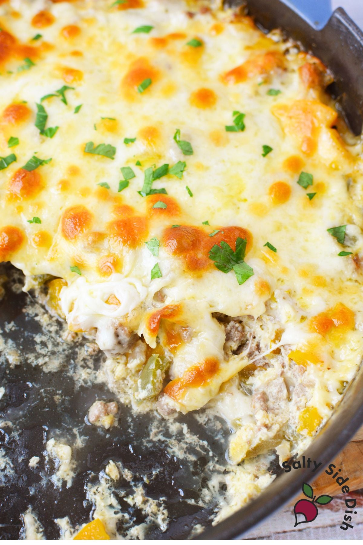 Close up of philly cheesesteak casserole with a portion scooped out showing the beef and pepper filling