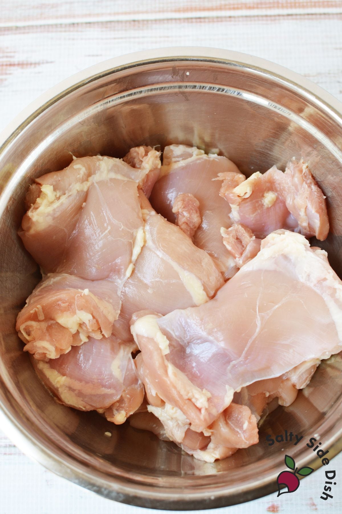 Boneless skinless chicken thighs in a mixing bowl for meal prep