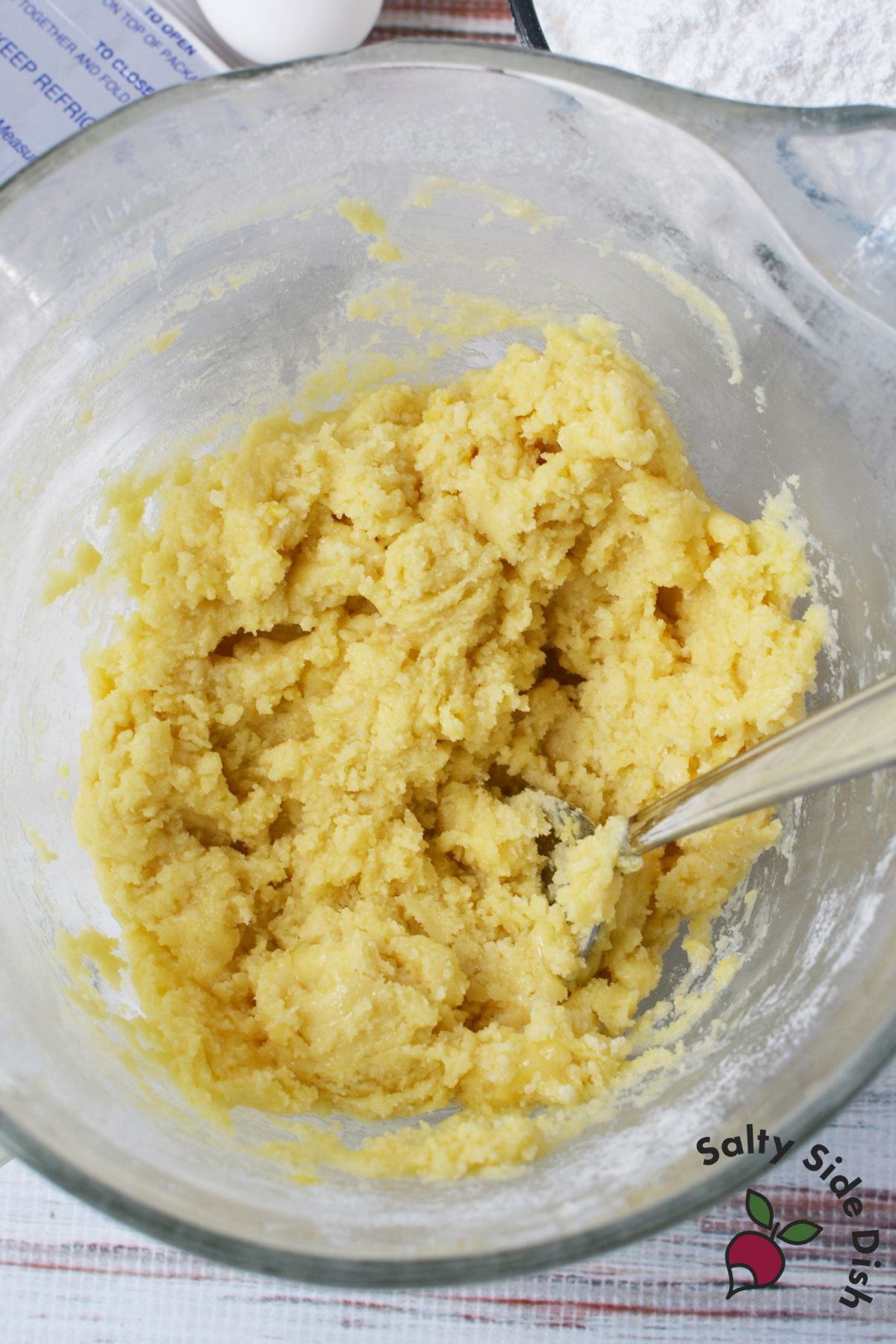 Lemon cookie bar dough mixed in a glass bowl before pressing into the baking pan