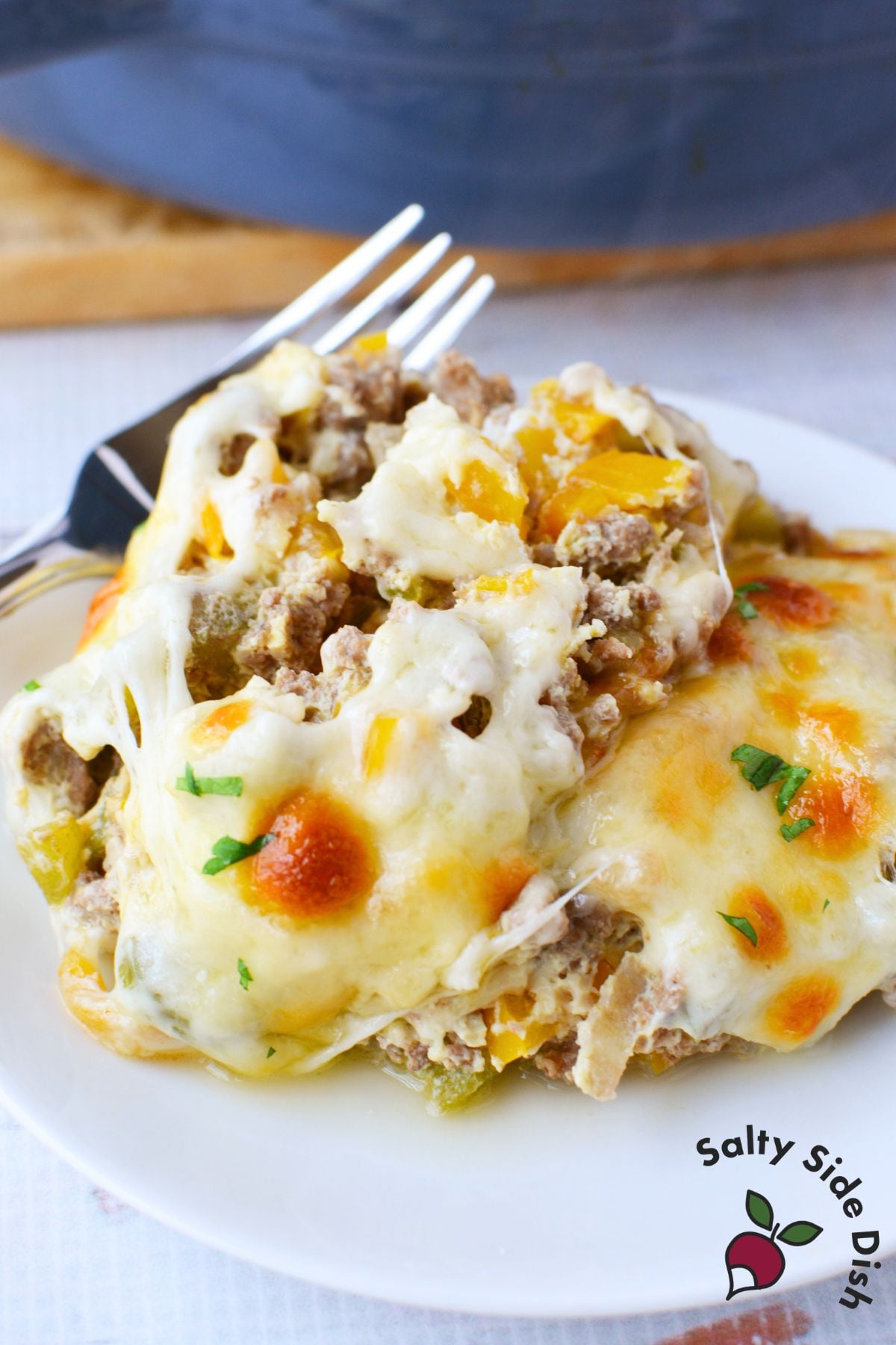 Plated serving of philly cheesesteak casserole with melted cheese and a fork