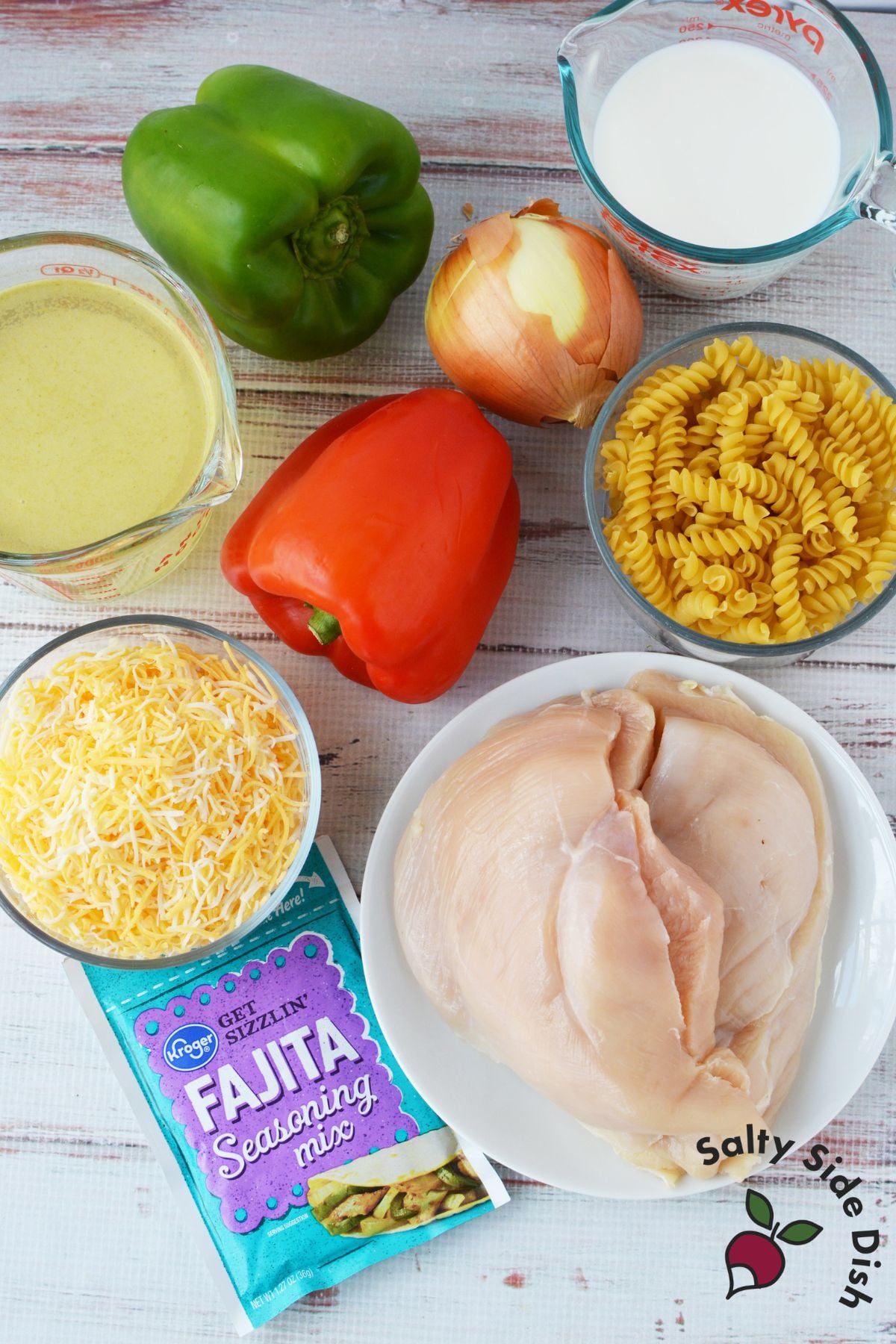 Ingredients for fajita chicken mac and cheese including chicken breast, peppers, onion, rotini, cheese, and fajita seasoning