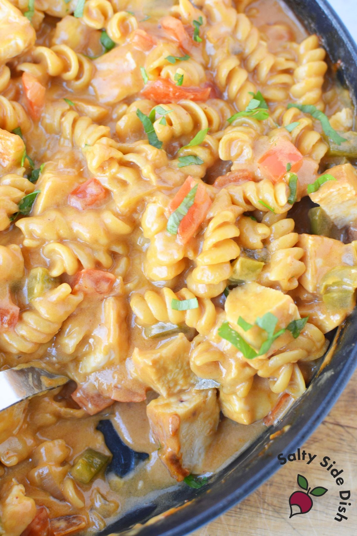 Overhead close up of fajita pasta dinner with chicken, peppers, and melted cheese in a skillet