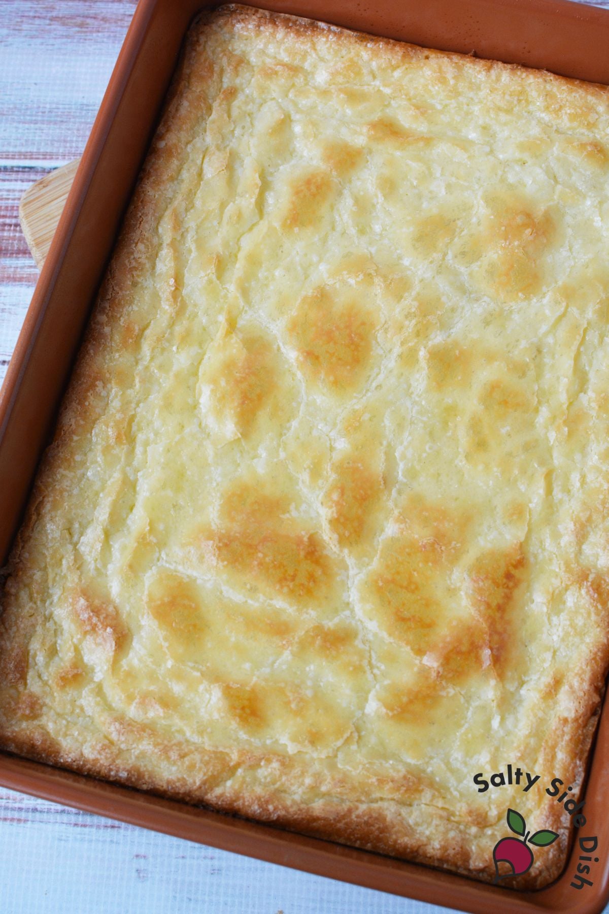 Freshly baked lemon cookie bars cooling in a baking pan with golden edges