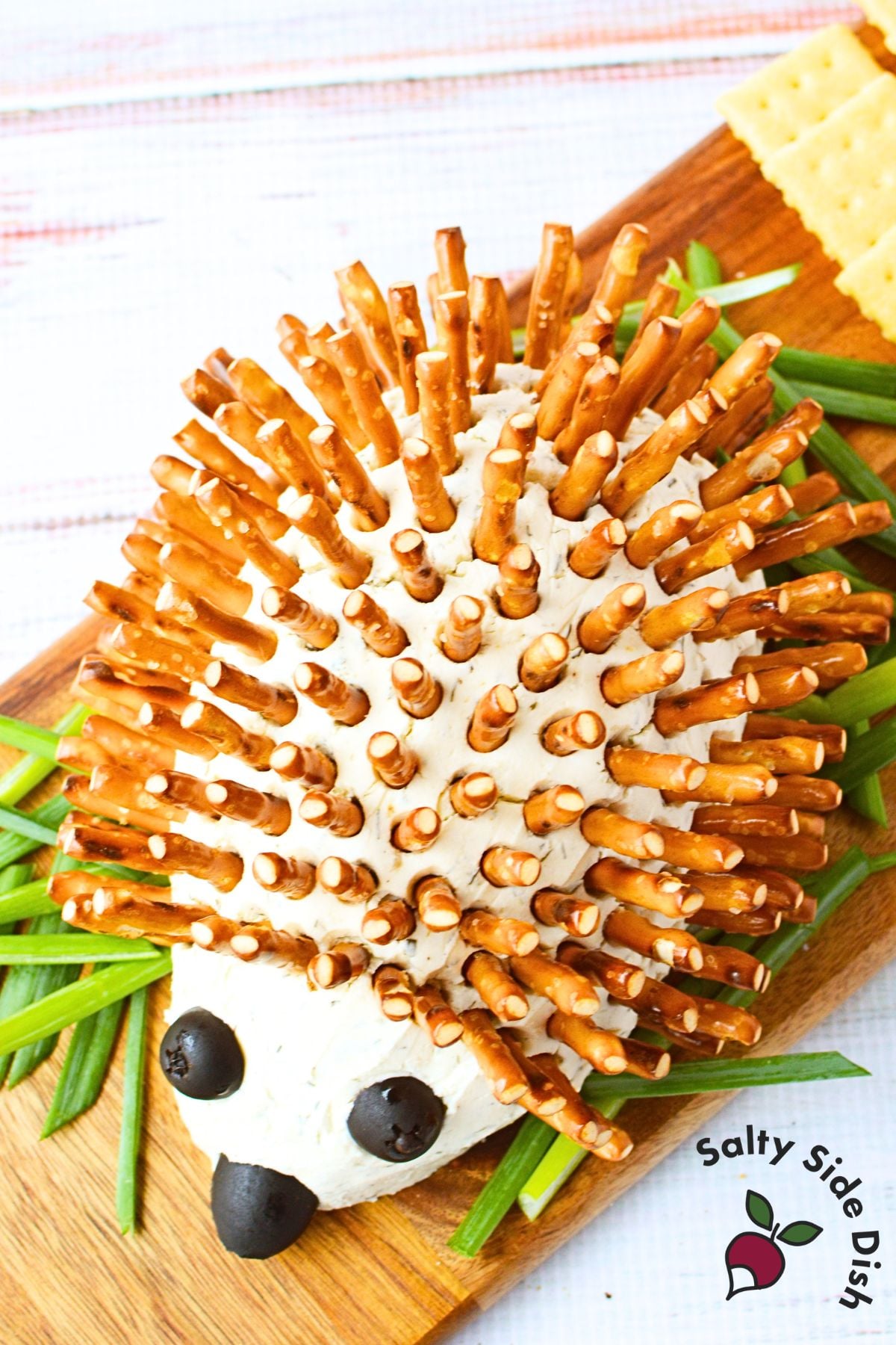overhead view of hedgehog cheeseball ingredients including Boursin shallot and chive, cream cheese, black olives, pretzel sticks, and seasonings