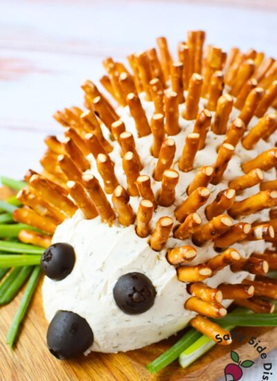 overhead view of hedgehog cheeseball ingredients including Boursin shallot and chive, cream cheese, black olives, pretzel sticks, and seasonings