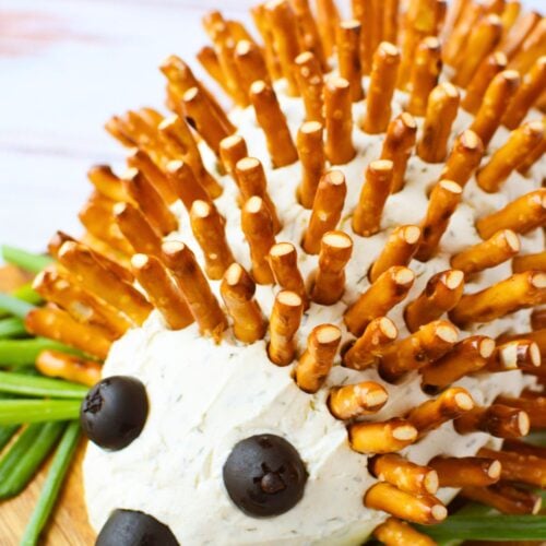 overhead view of hedgehog cheeseball ingredients including Boursin shallot and chive, cream cheese, black olives, pretzel sticks, and seasonings