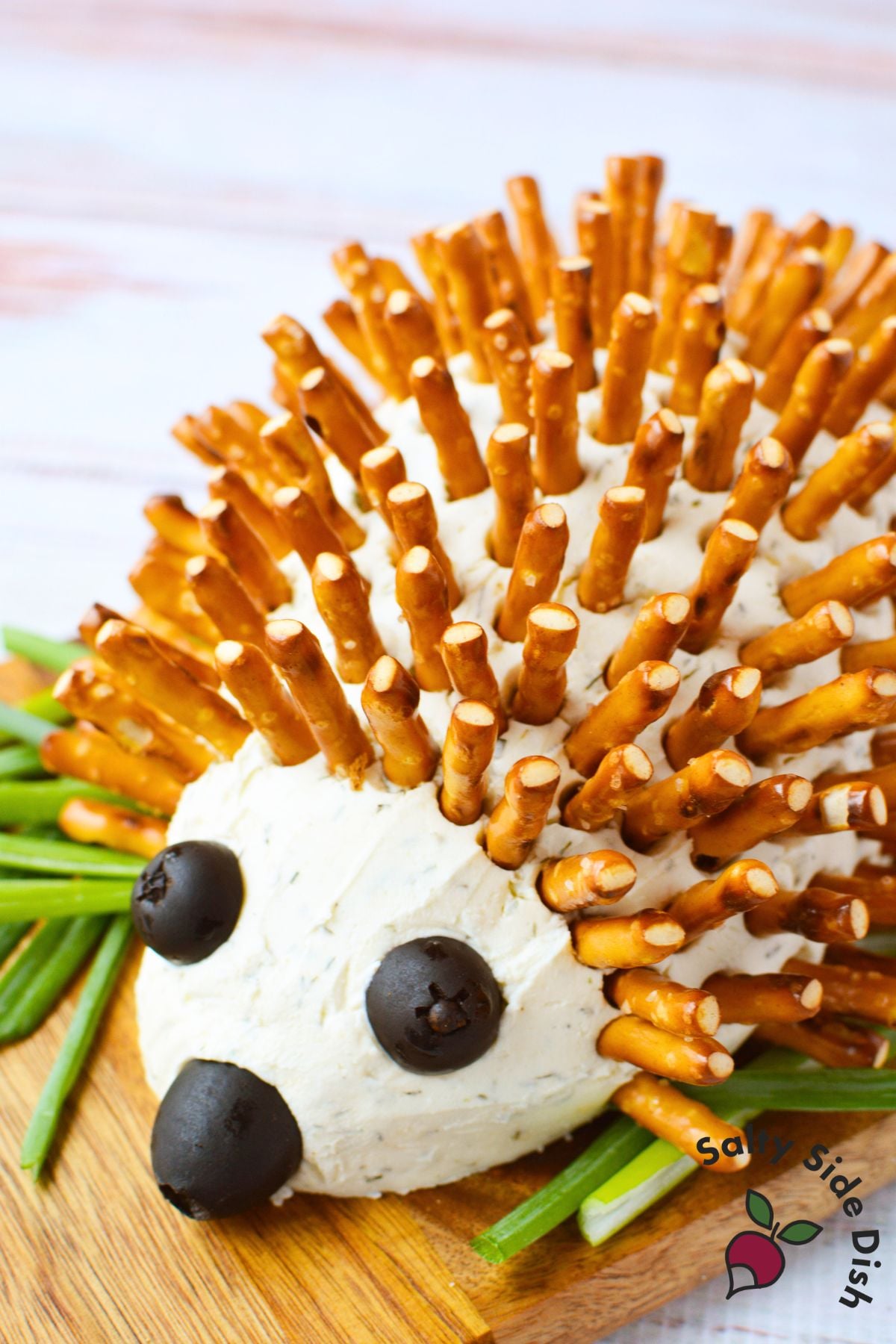 overhead view of hedgehog cheeseball ingredients including Boursin shallot and chive, cream cheese, black olives, pretzel sticks, and seasonings