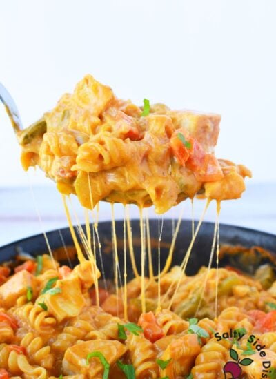 Spoonful of one pan fajita chicken pasta lifted from the skillet with a melted cheese pull