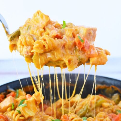 Spoonful of one pan fajita chicken pasta lifted from the skillet with a melted cheese pull