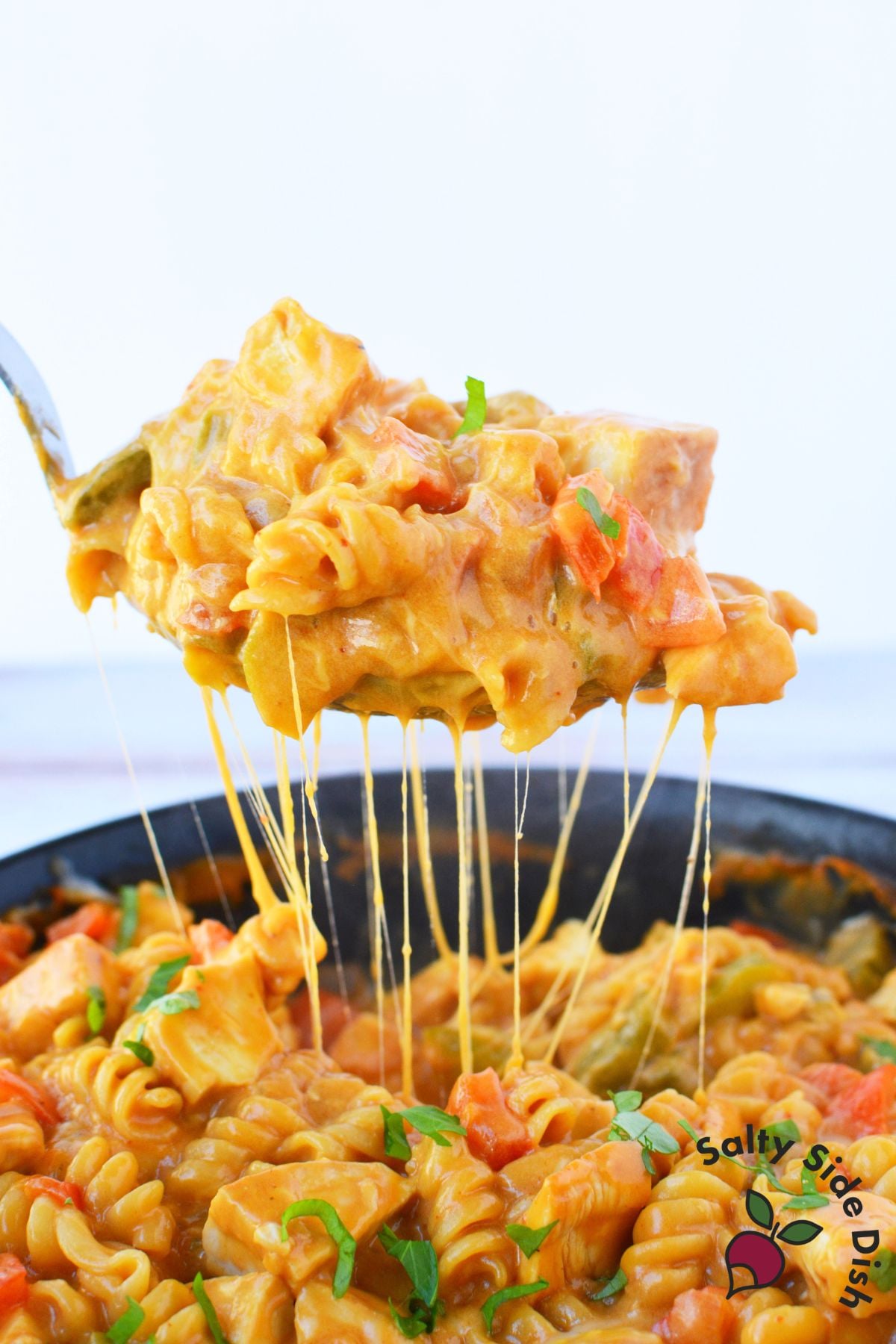 Spoonful of one pan fajita chicken pasta lifted from the skillet with a melted cheese pull