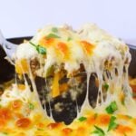 Spoonful of philly cheesesteak casserole lifted from the skillet with a stretchy cheese pull