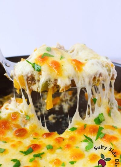 Spoonful of philly cheesesteak casserole lifted from the skillet with a stretchy cheese pull