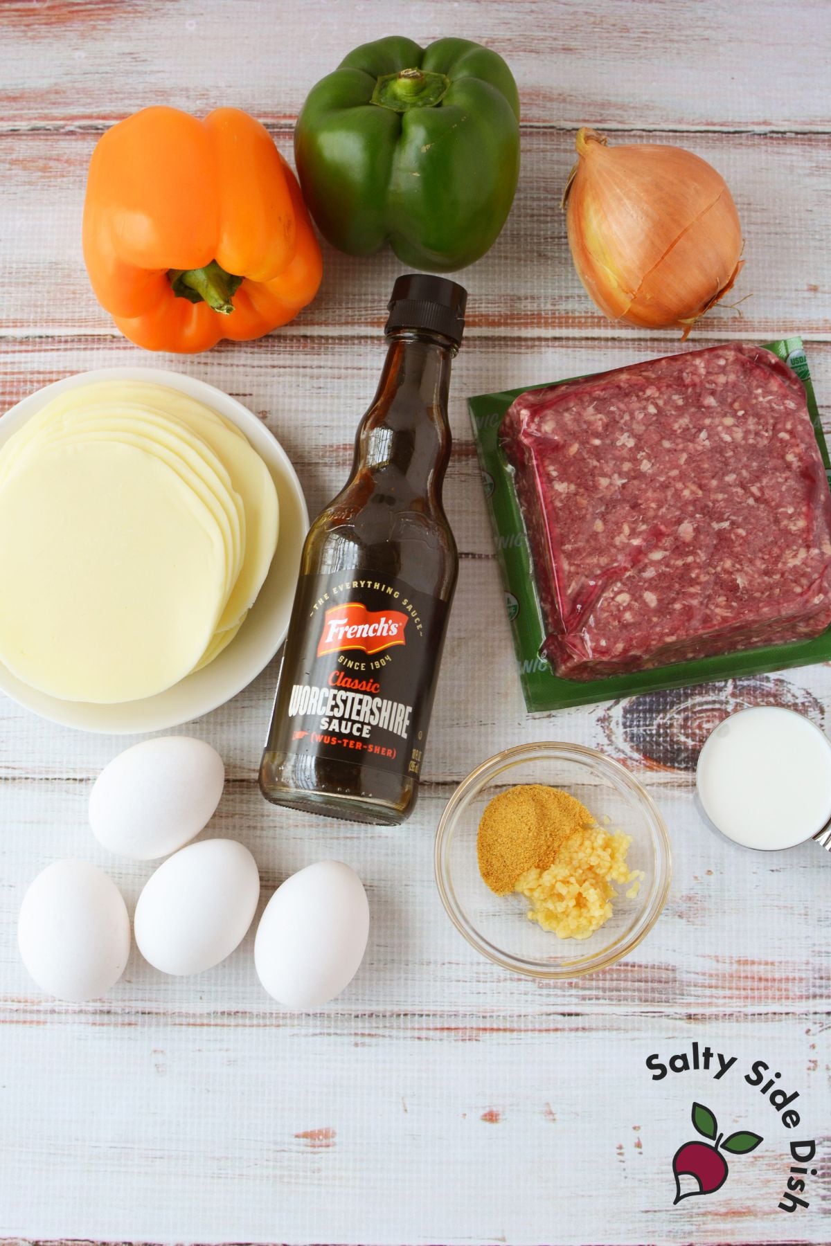 Ingredients for philly cheesesteak casserole including ground beef, peppers, onion, provolone, eggs, garlic, and Worcestershire sauce