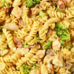 Close-up of cheesy chicken bacon pasta with rotini, broccoli, carrots, and creamy sauce.
