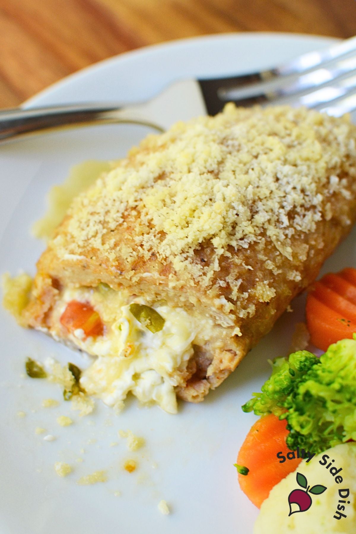 Chicken pocket cut in half on a plate with carrots and broccoli, revealing melted cream cheese filling