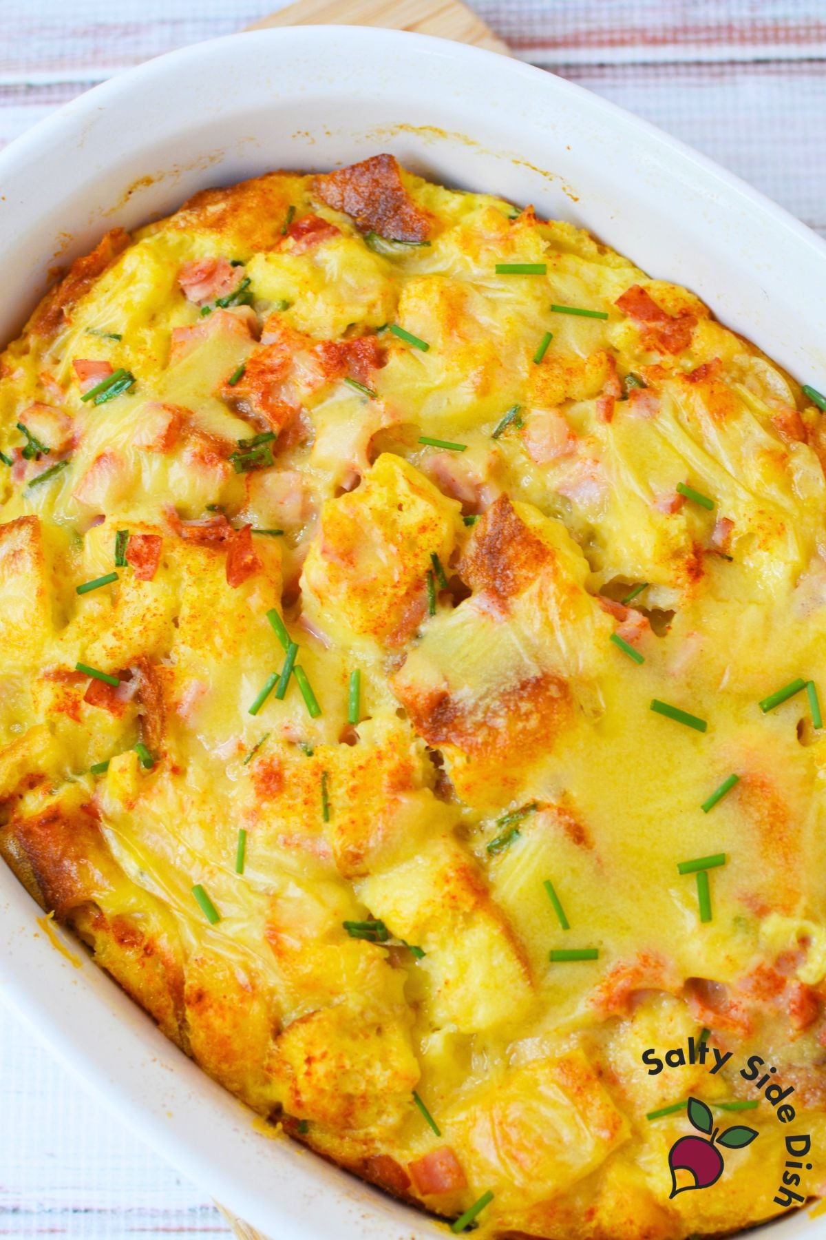 Overhead view of baked eggs benedict casserole topped with hollandaise and chives