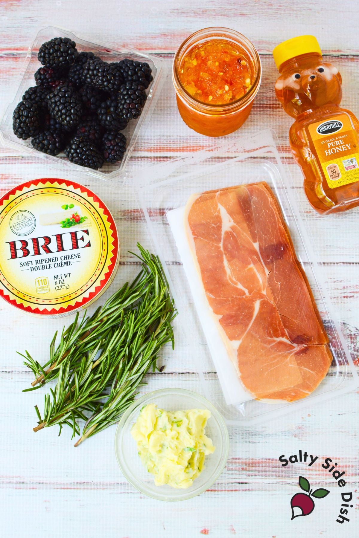 Close up of melted brie charcuterie dip with prosciutto, blackberries, and pepper jelly