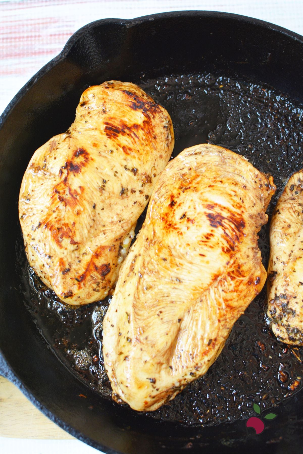 Marinated chicken breasts searing in a cast iron skillet