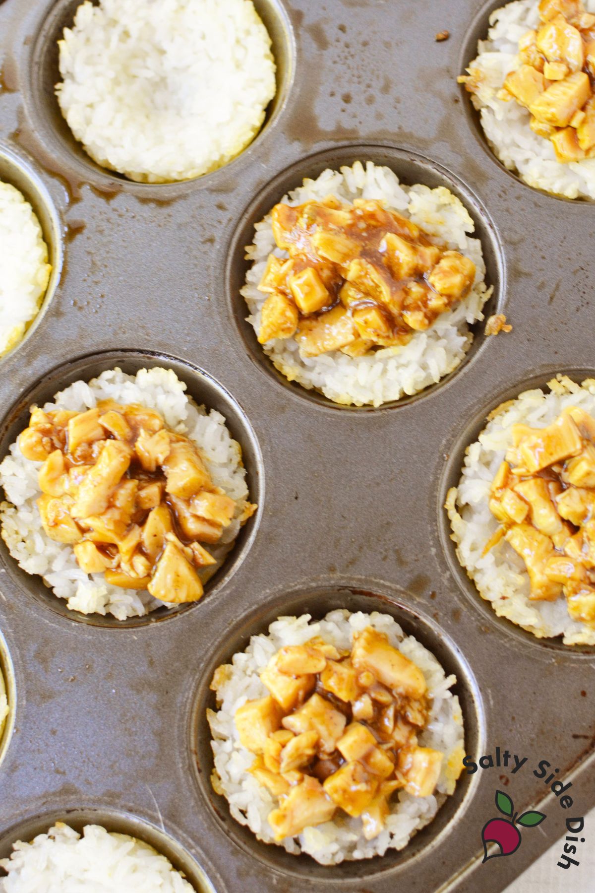 Baked rice cups filled with teriyaki chicken in a muffin tin