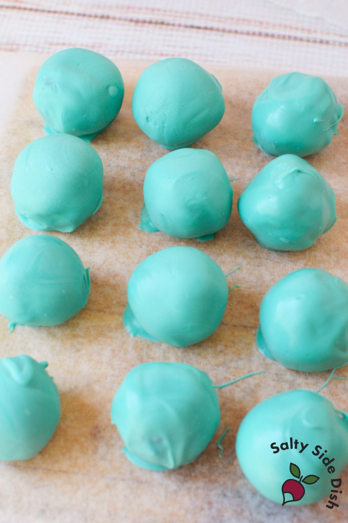 Freshly dipped Oreo truffles cooling on parchment paper before decorating.