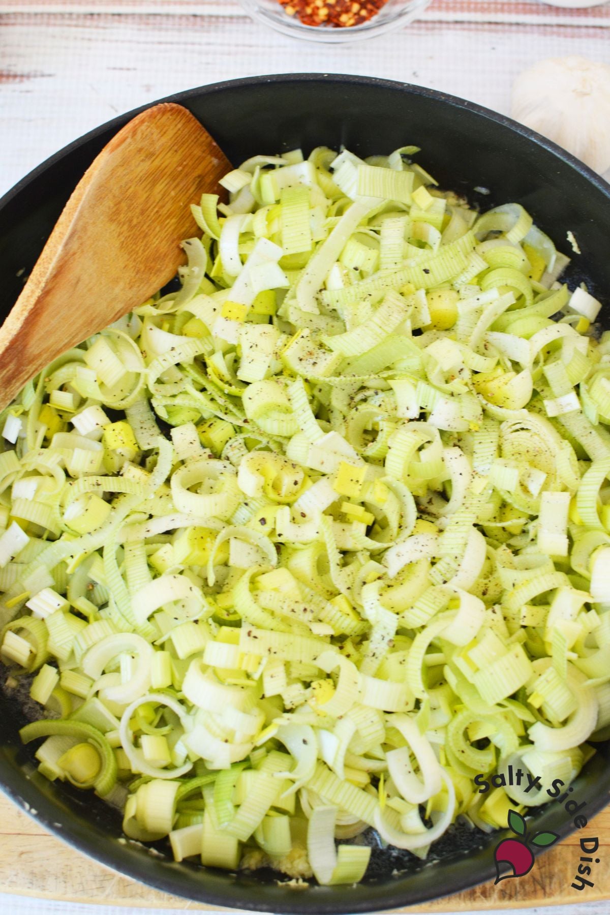adding fresh leeks to a cast iron pan and seasoning.