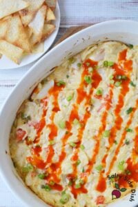 Baked crab rangoon dip topped with sriracha drizzle and green onions