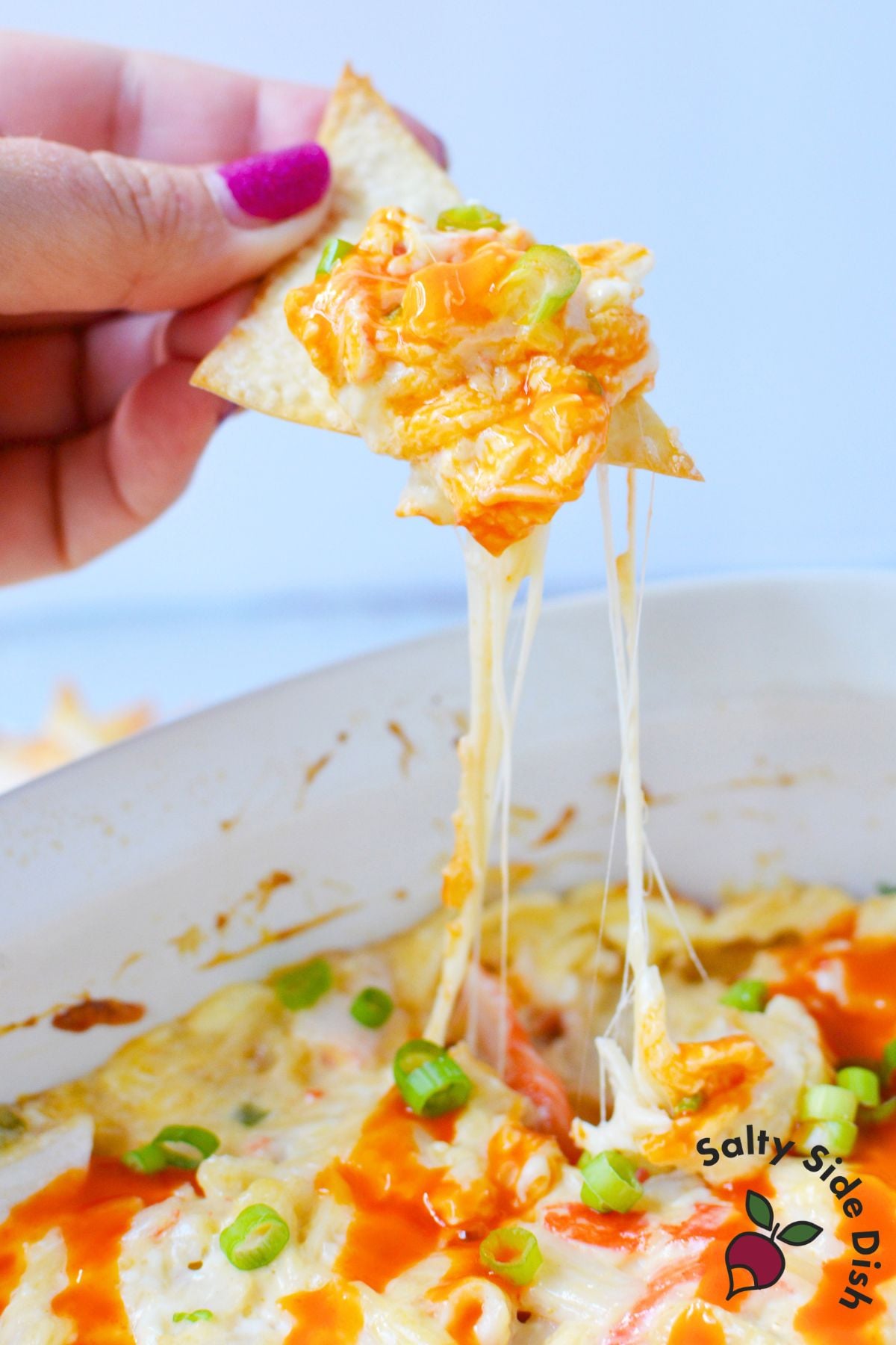 Wonton chip lifted from crab rangoon dip with melted cheese pulling