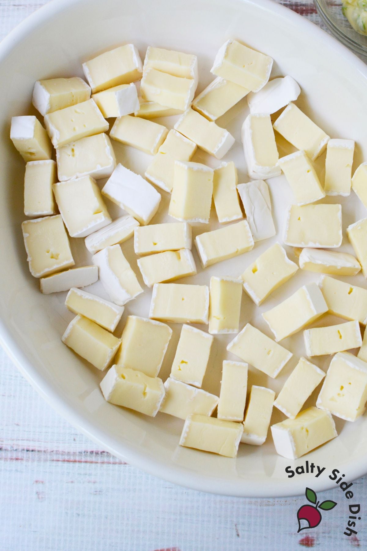 Brie cheese cut into half inch cubes in a baking dish before adding toppings