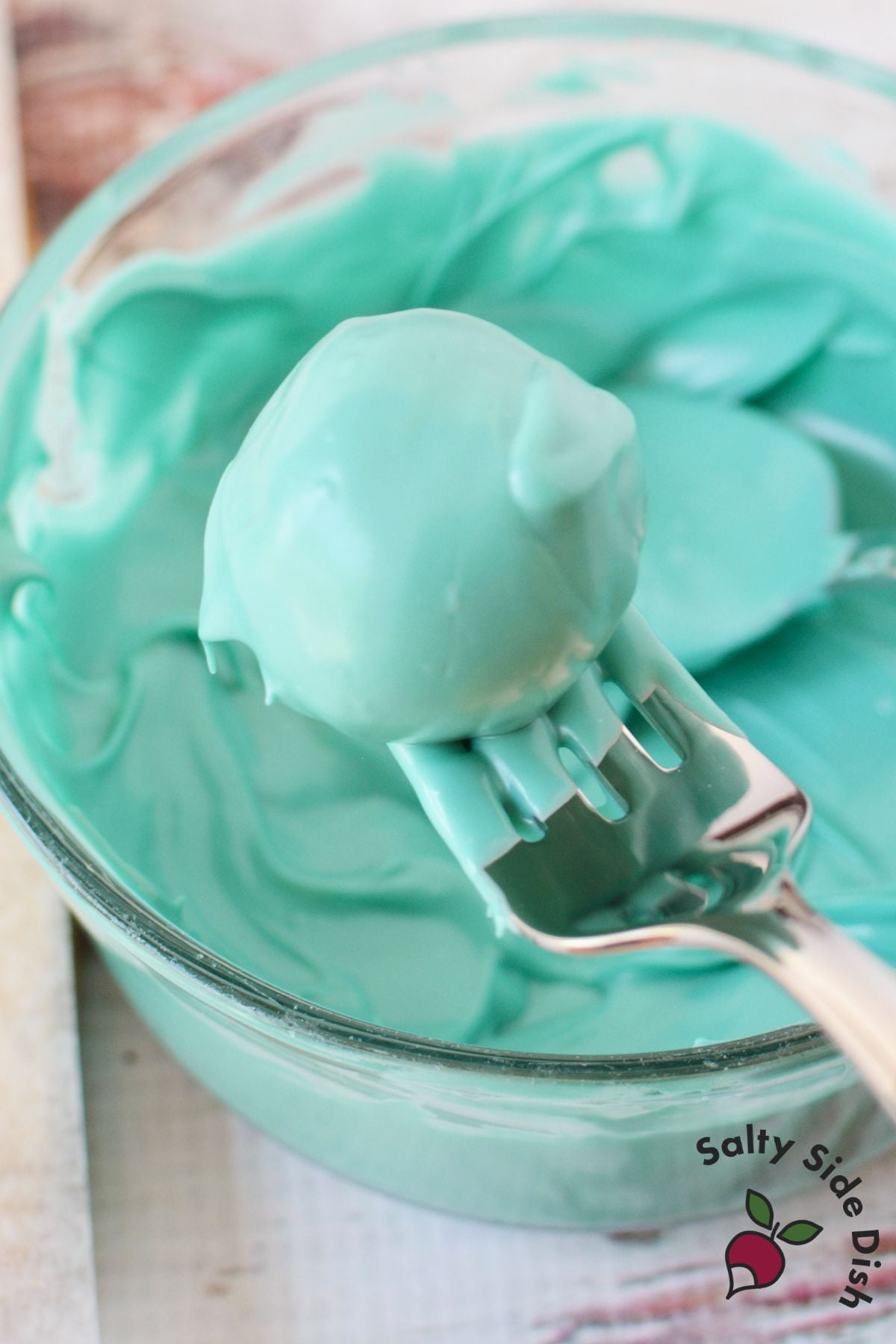 Chilled Oreo truffle coated in melted turquoise candy melts before decorating.