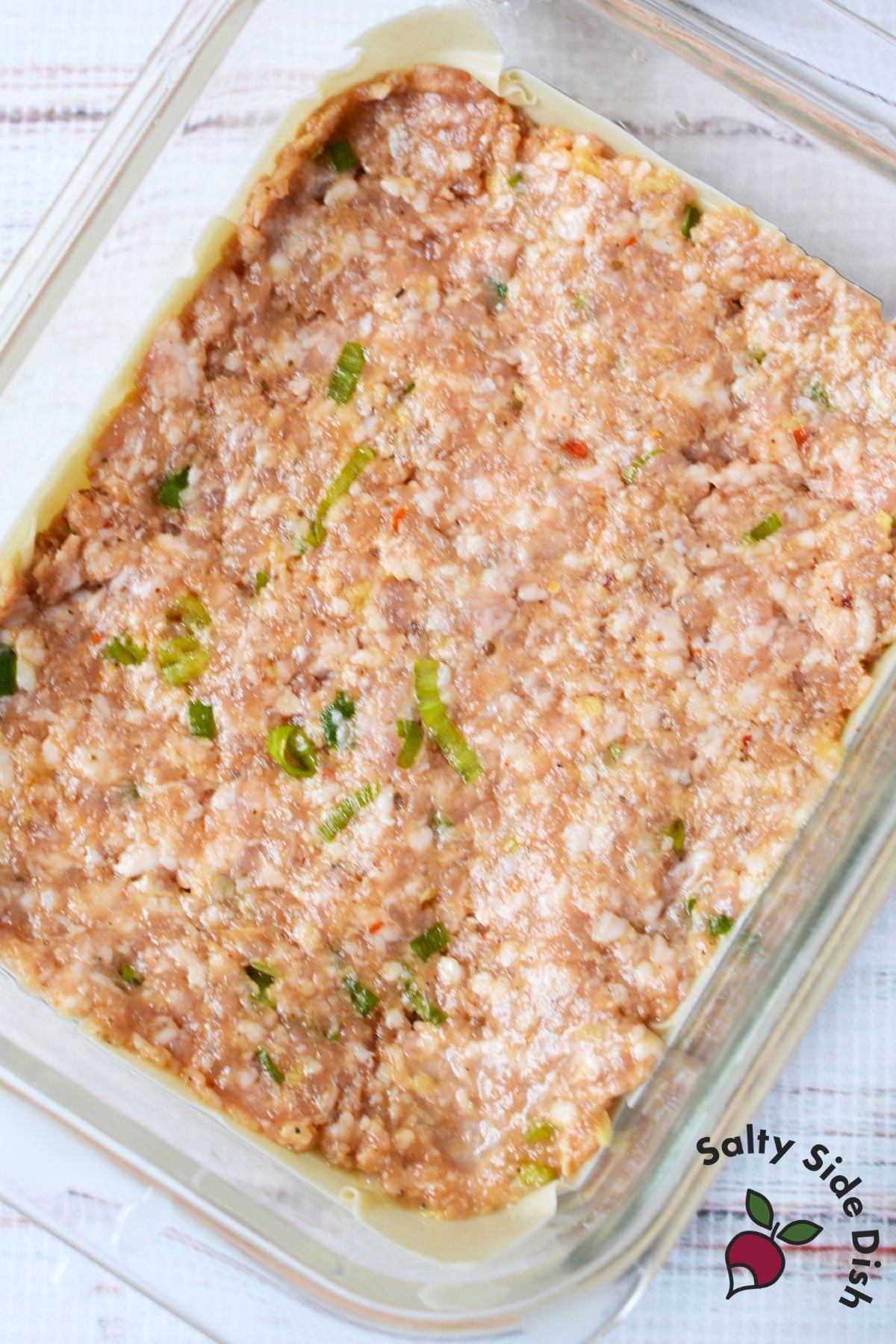 Seasoned ground pork filling spread over wonton wrappers for dumpling lasagna.