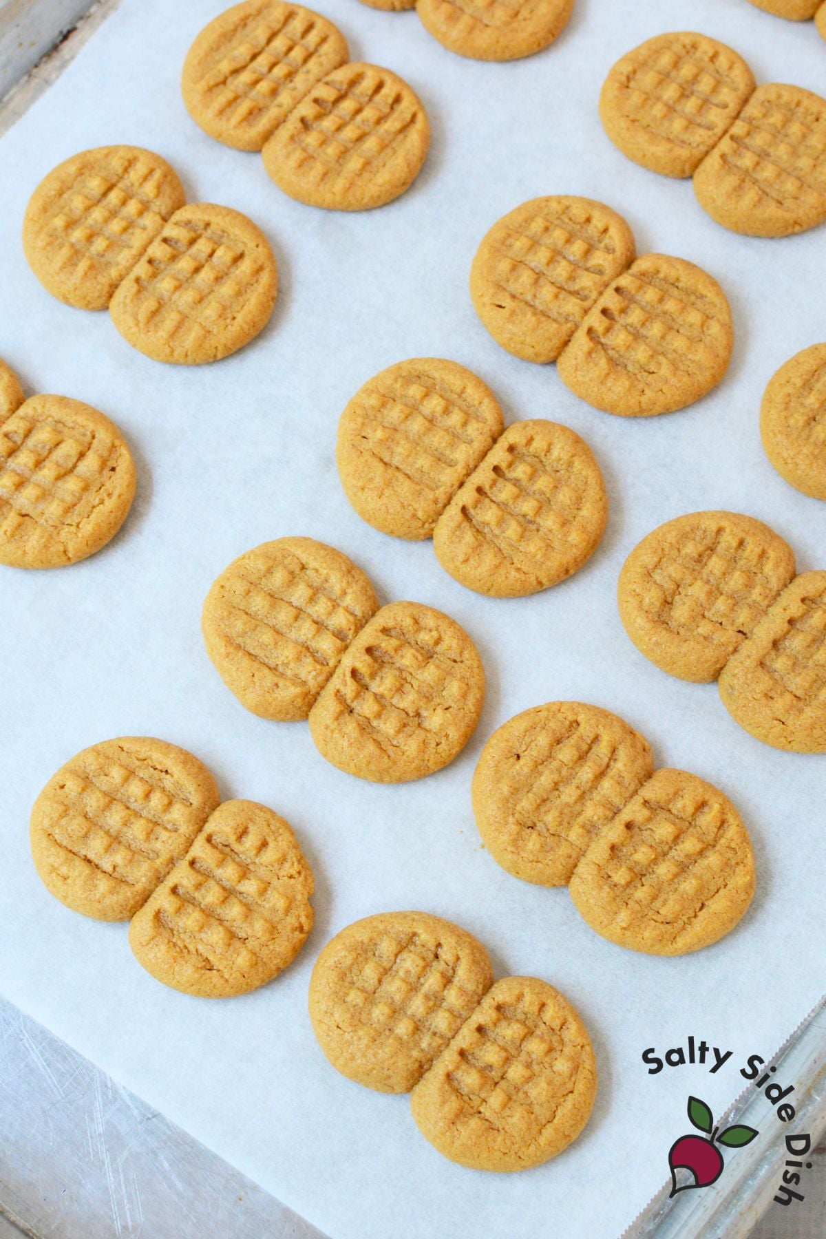 Unbaked nutter butter cookie dough pressed into a crosshatch pattern on a parchment lined baking sheet