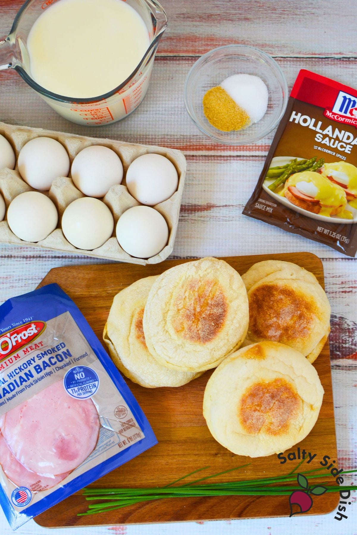 Milk, eggs, English muffins, Canadian bacon, and hollandaise sauce mix on a wood board