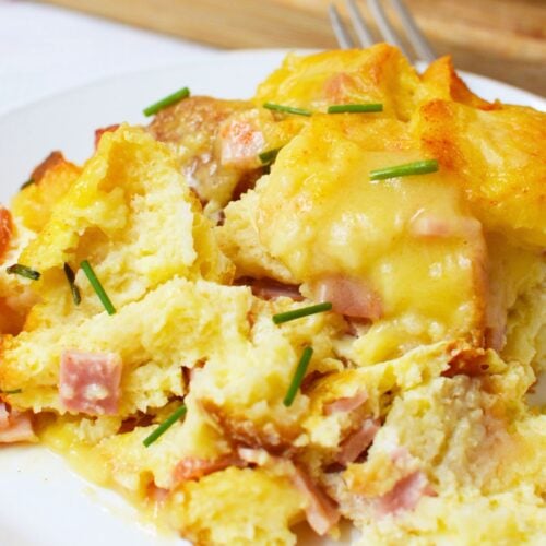 Plated slice of eggs benedict casserole with Canadian bacon and fresh chives