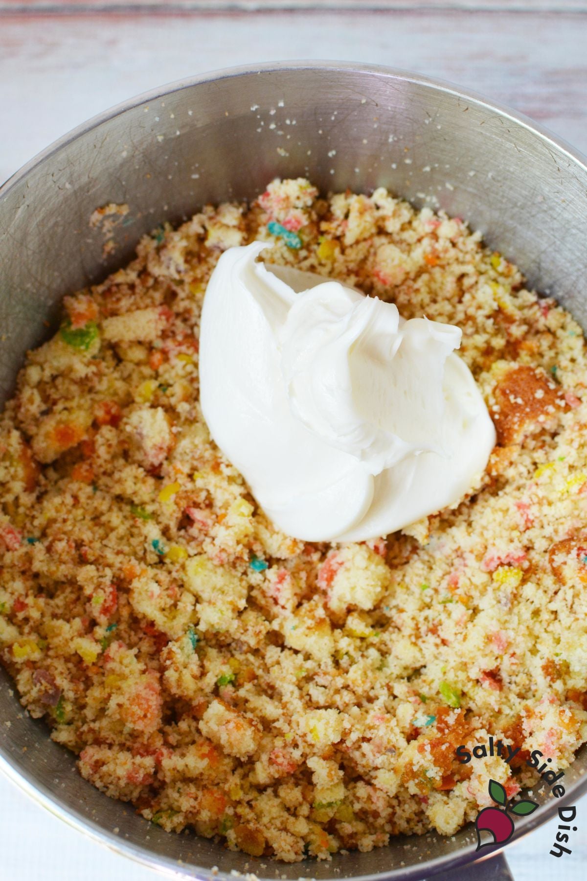 Cake crumbles with cream cheese frosting added in a bowl